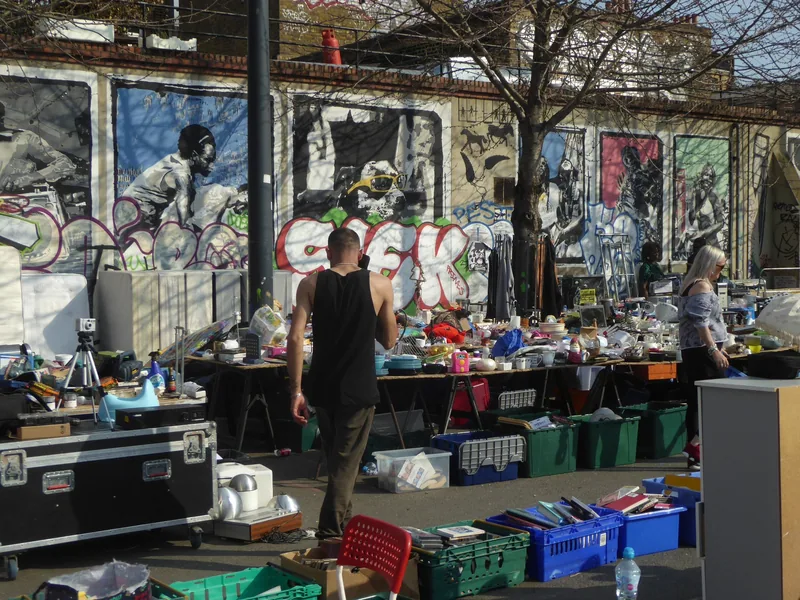 A bric-a-brac stall at Deptford market set out in front of a large painted mural