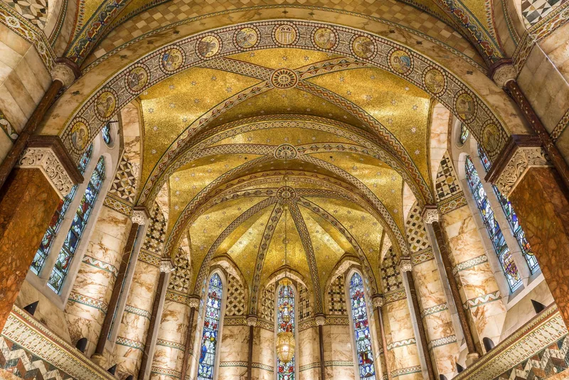 The gold mosaic vaulted ceiling and stained glass windows inside Fitzrovia Chapel