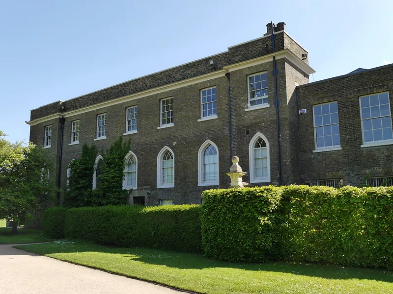 Georgian stone range at Fulham Palace behind a clipped hedge in summer sunshine