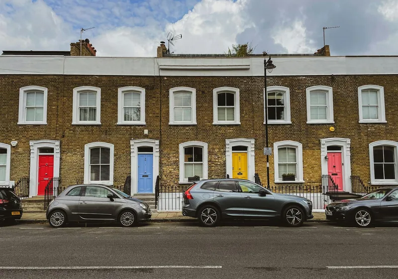 A brick terrace with brightly painted front doors and cars parked along an Islington street