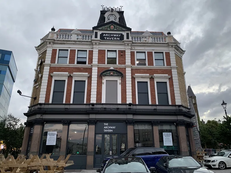 The Archway Tavern, a red brick corner pub with its name across the gable, at the Archway junction