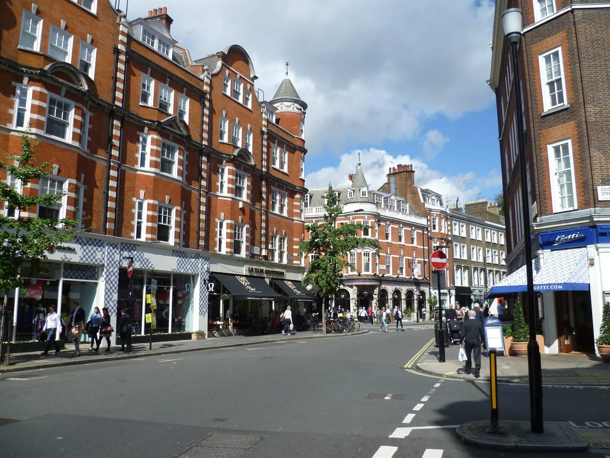Red-brick mansion blocks and shopfronts along Marylebone High Street on a sunny day