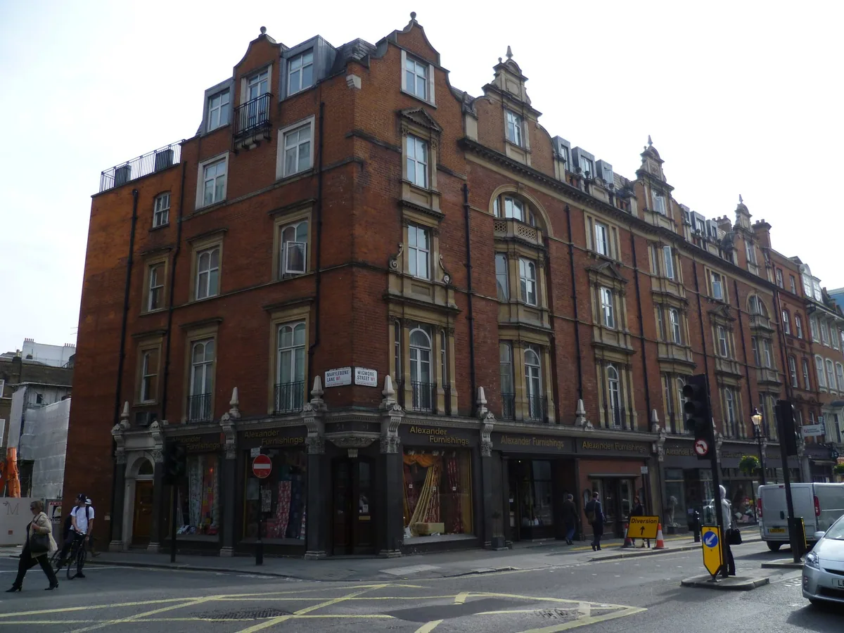A tall red-brick Victorian corner block where Marylebone Lane meets Wigmore Street, the street sign fixed under its first-floor windows