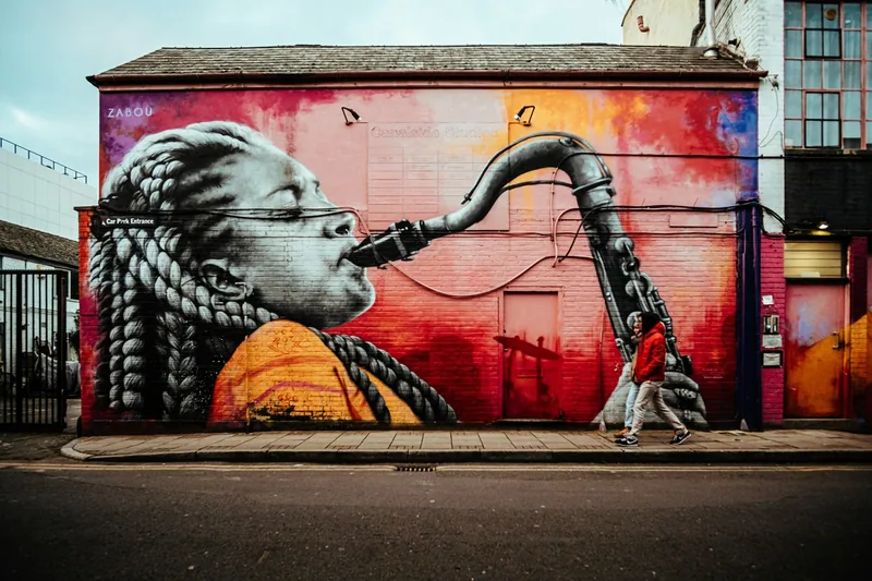 A large mural of a saxophone player covering the end wall of a Shoreditch building