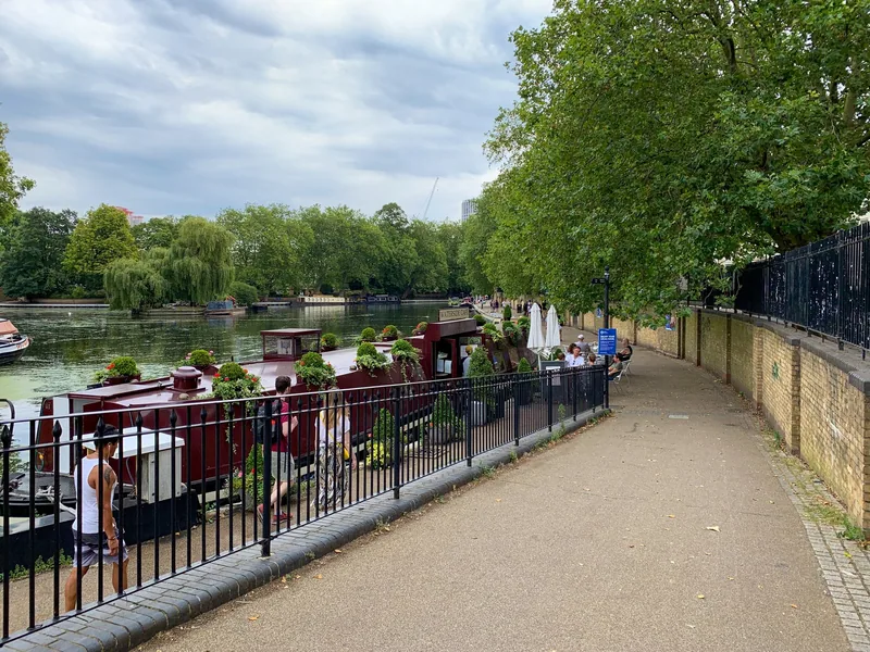 Narrowboats moored along the canal at Little Venice, with a tree-lined towpath beside them