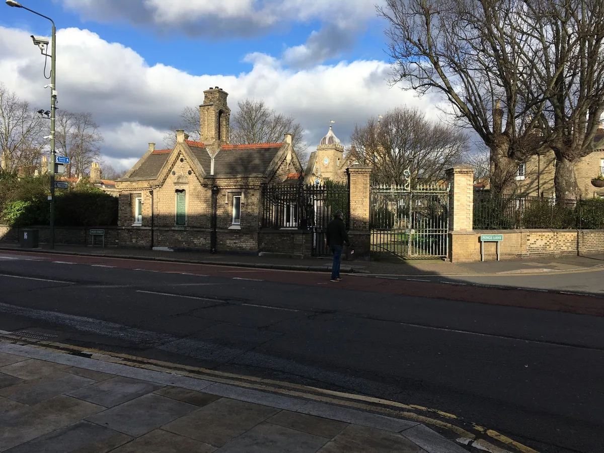 The yellow-brick lodges and iron gates of the Watermen's almshouses on Penge Lane, seen from across the road