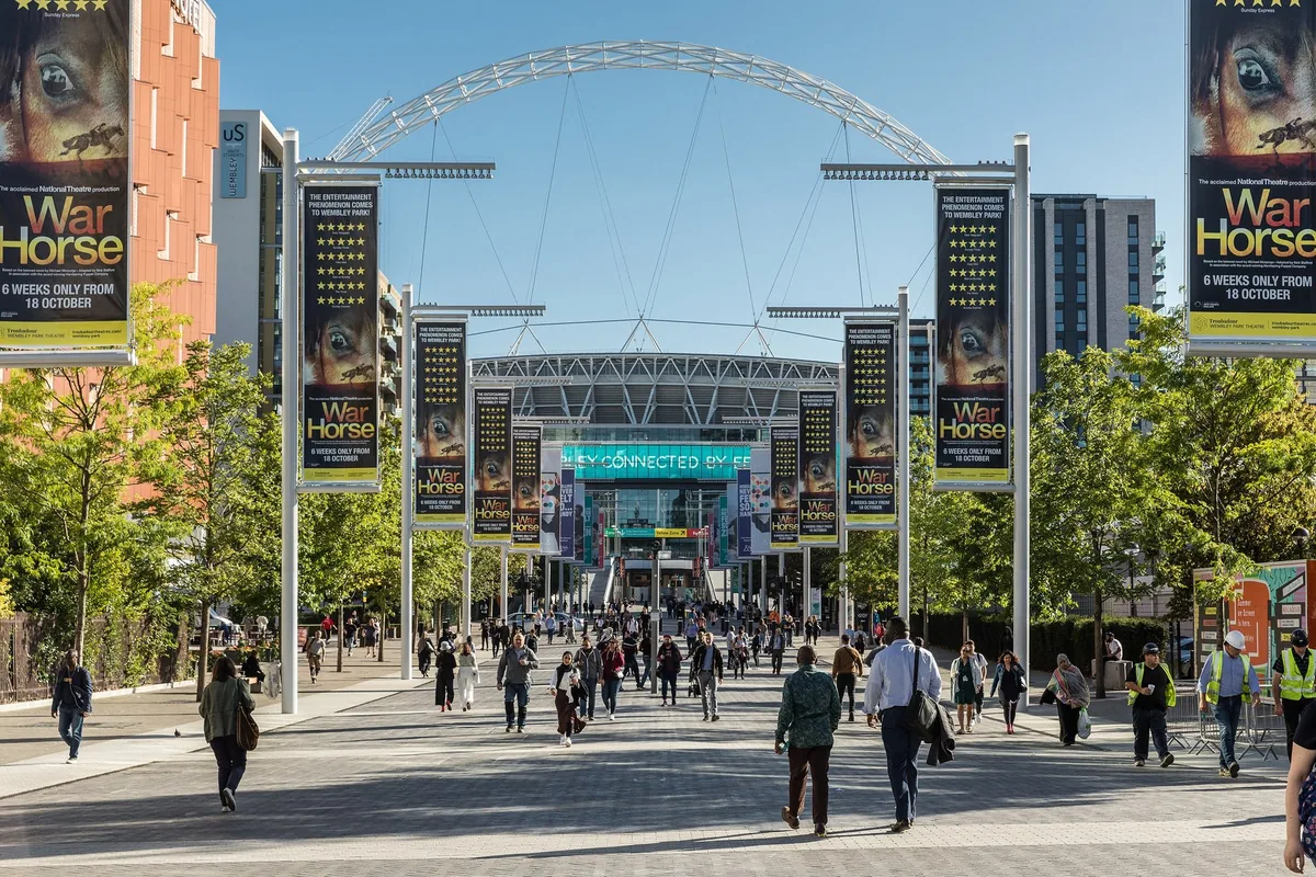 Olympic Way in Wembley Park, a wide pedestrian avenue leading towards the white arch of Wembley Stadium