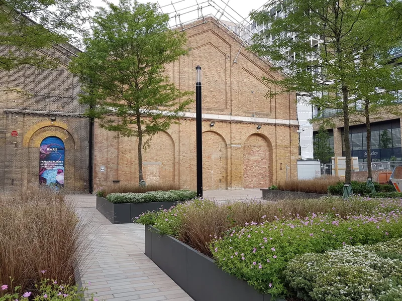 Planted square at the Royal Arsenal in Woolwich beside old brick warehouse gables
