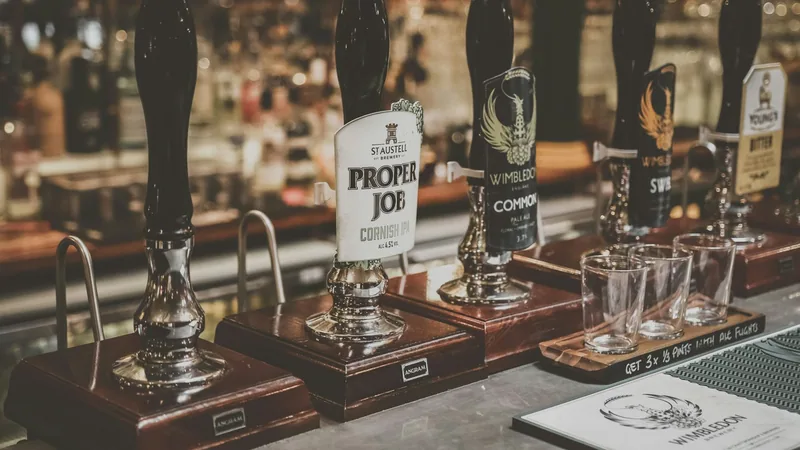 Cask ale hand pumps with pump clips on a pub bar, with empty glasses lined up beside them