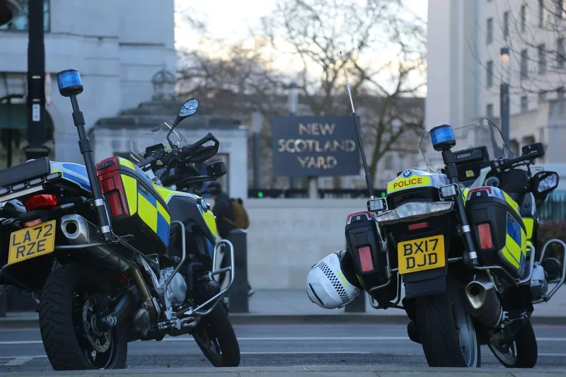 Two Metropolitan Police motorcycles parked outside the New Scotland Yard sign