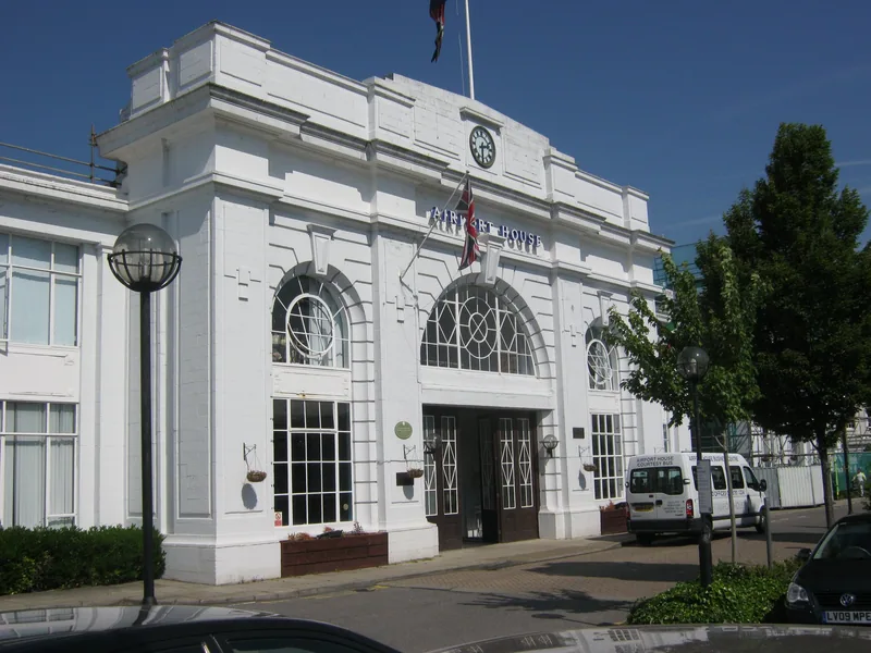 The entrance of Airport House at Croydon, a white rendered facade with arched windows, a clock and the name across the parapet