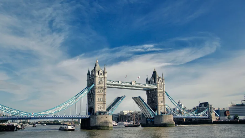 Tower Bridge with its bascules raised under a blue sky with streaks of cloud