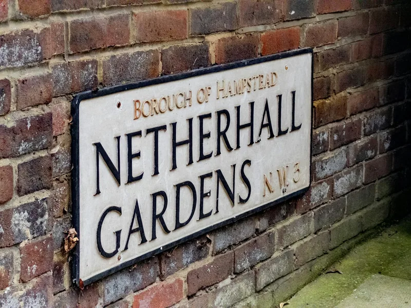 An older street sign on a brick wall reading Netherhall Gardens NW3, Borough of Hampstead