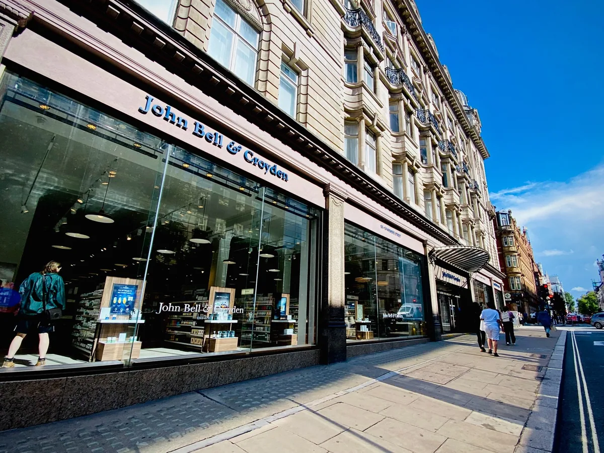 The long glass shop front of John Bell and Croyden chemists on Wigmore Street in London, lit by afternoon sun