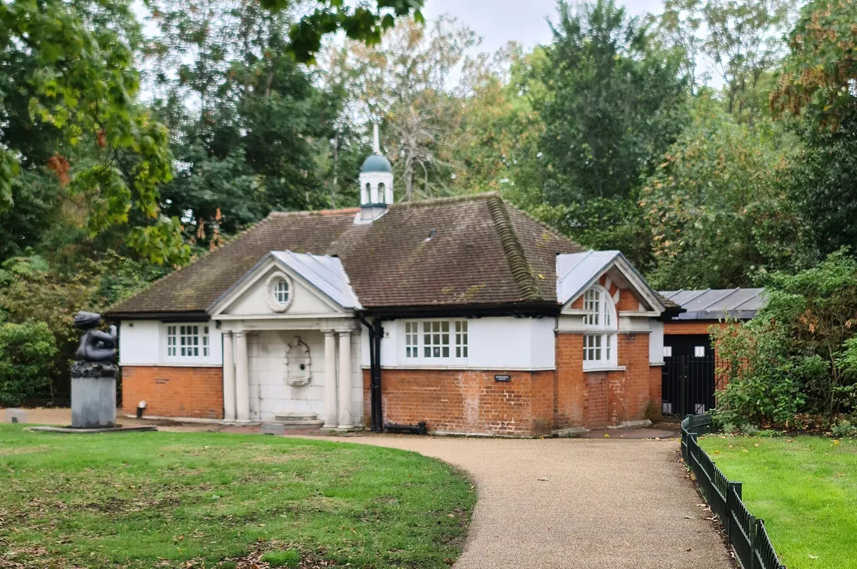 Small brick and white public toilet building beside a path and lawn in Hyde Park
