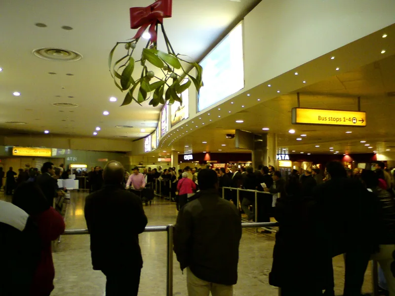 Travellers with luggage trolleys in the international arrivals hall at Heathrow Terminal 1