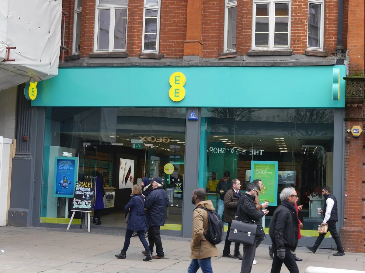 Shoppers walking past an EE mobile phone shop on Oxford Street in London