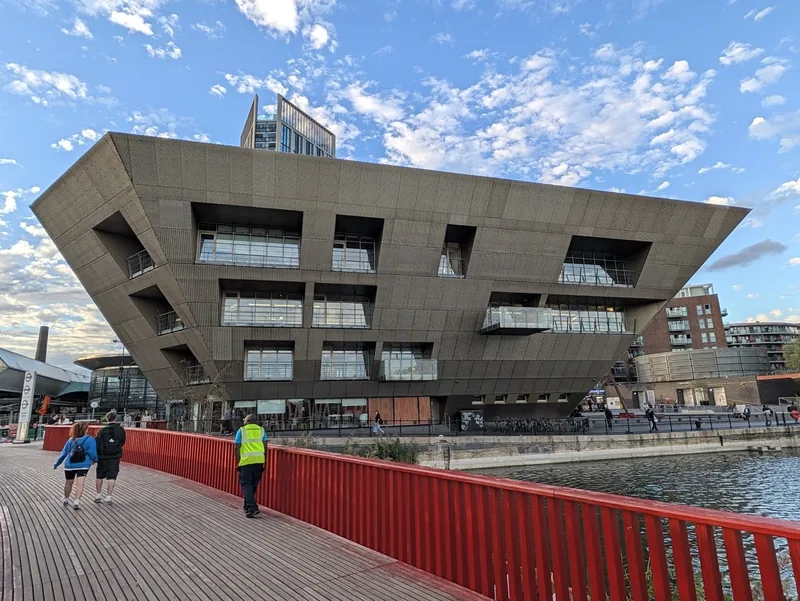 The wedge-shaped Canada Water Library beside the dock, seen from the red footbridge