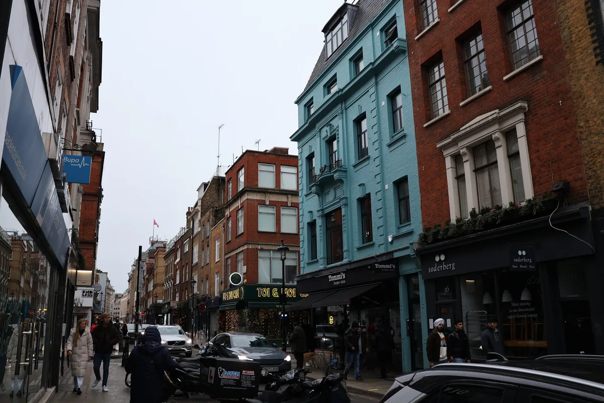 Berwick Street in Soho, with a turquoise-painted corner building and shopfronts along the pavement