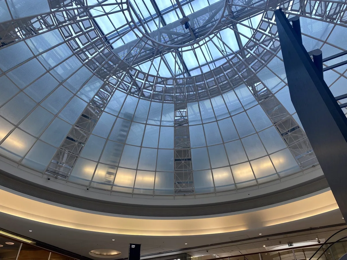 Looking up into the glazed steel dome over the central court of Brent Cross shopping centre