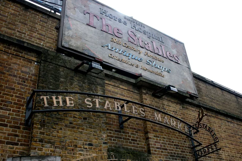 The wrought-iron Stables Market arch and the painted Horse Hospital sign on a brick wall at Camden