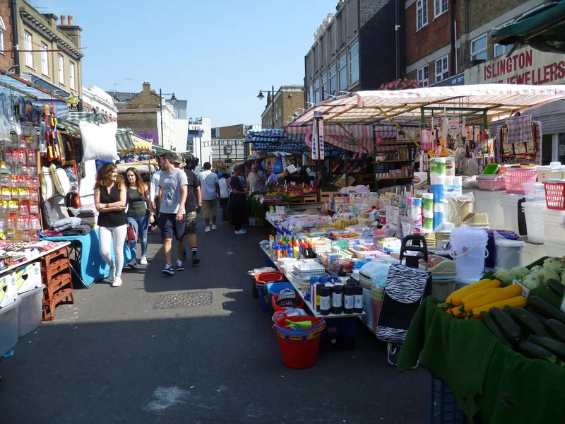 Household goods and produce stalls lining Chapel Market on a sunny trading day