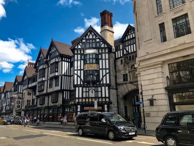Liberty's black and white timbered corner seen from the street with traffic passing