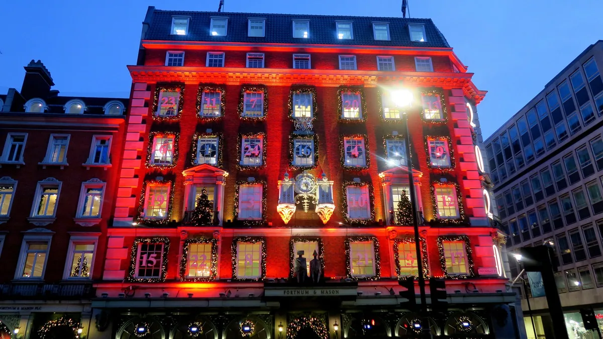 The Fortnum & Mason building on Piccadilly lit up red at night with its windows dressed as an advent calendar