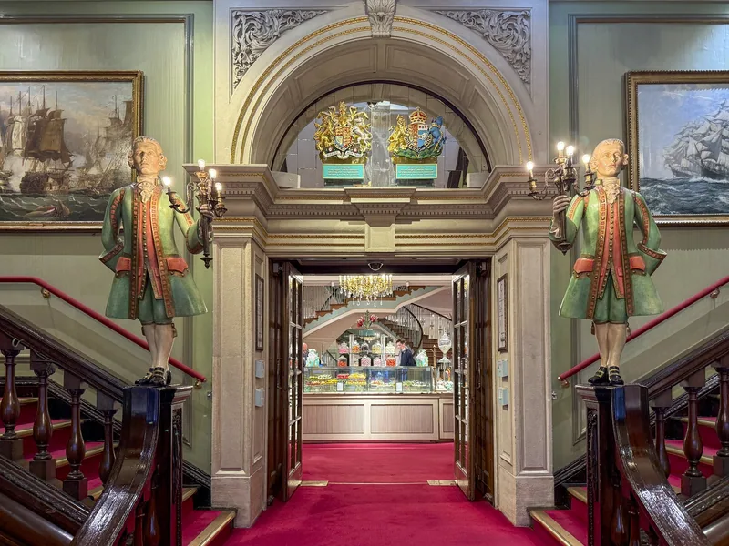 The entrance hall of Fortnum & Mason, with painted figures of Mr Fortnum and Mr Mason flanking a red-carpeted way in