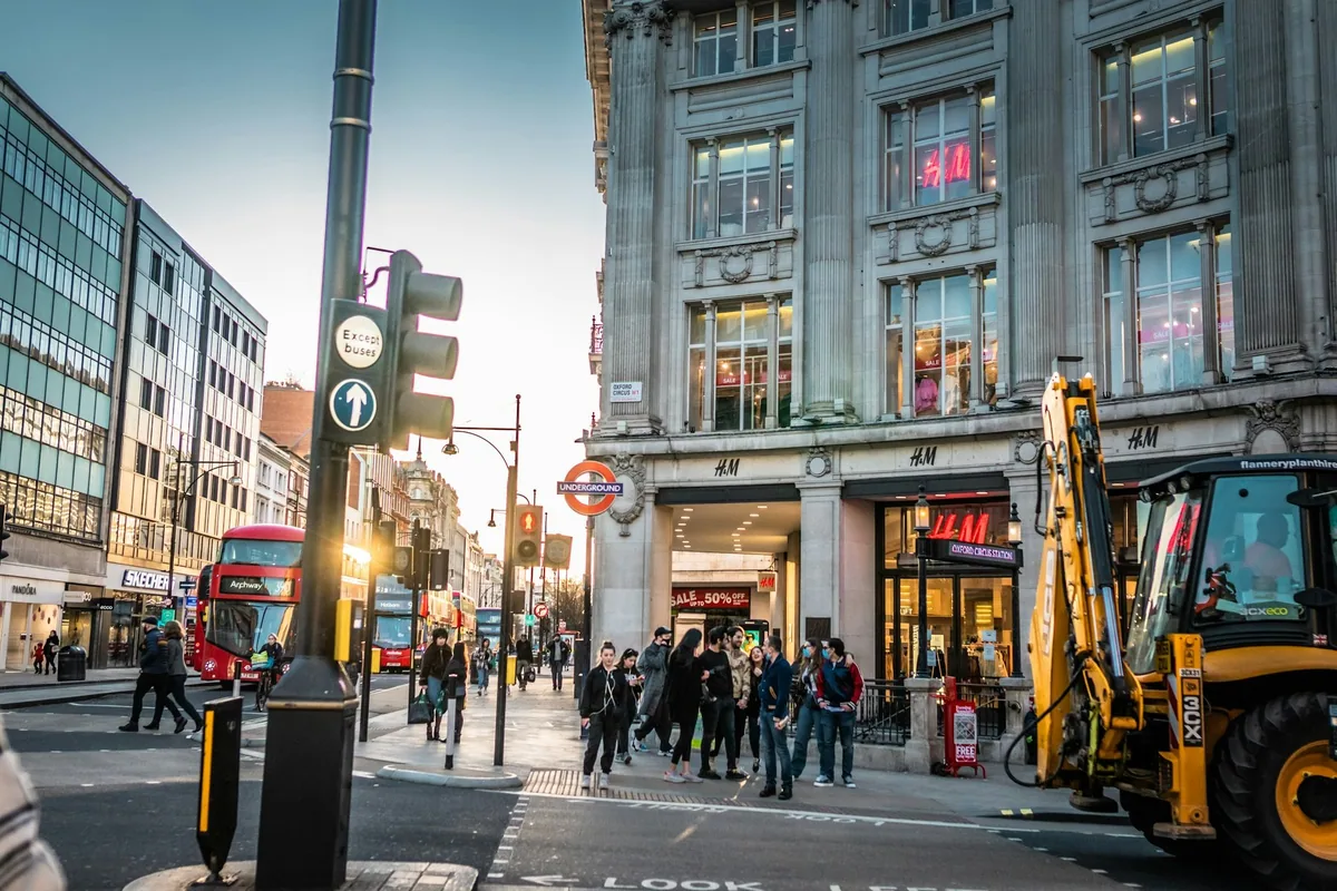 Shoppers crossing Oxford Street past a red double-decker bus and an Underground roundel