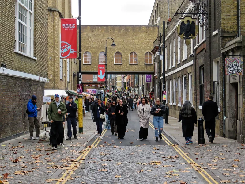 Sunday market crowds filling Brick Lane below the old brick railway bridge