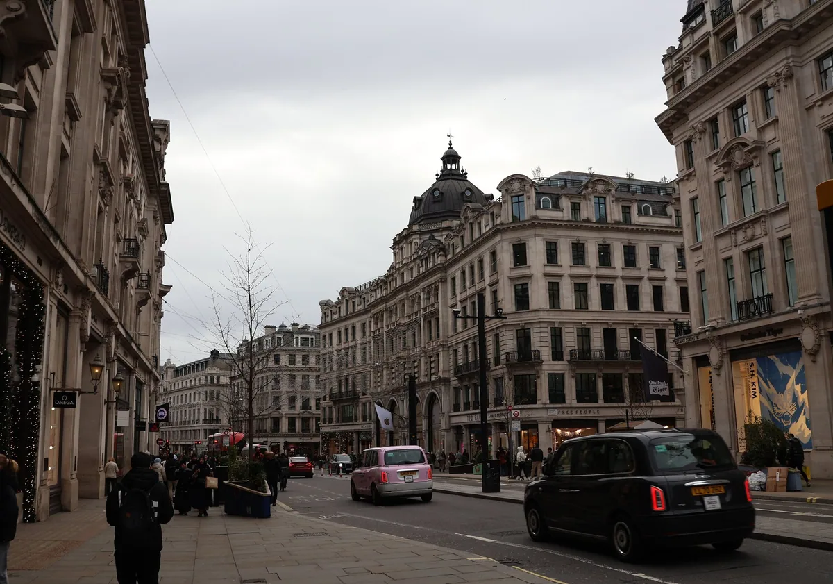 A black cab passing the curved stone shopfronts of Regent Street, with shoppers on the pavement