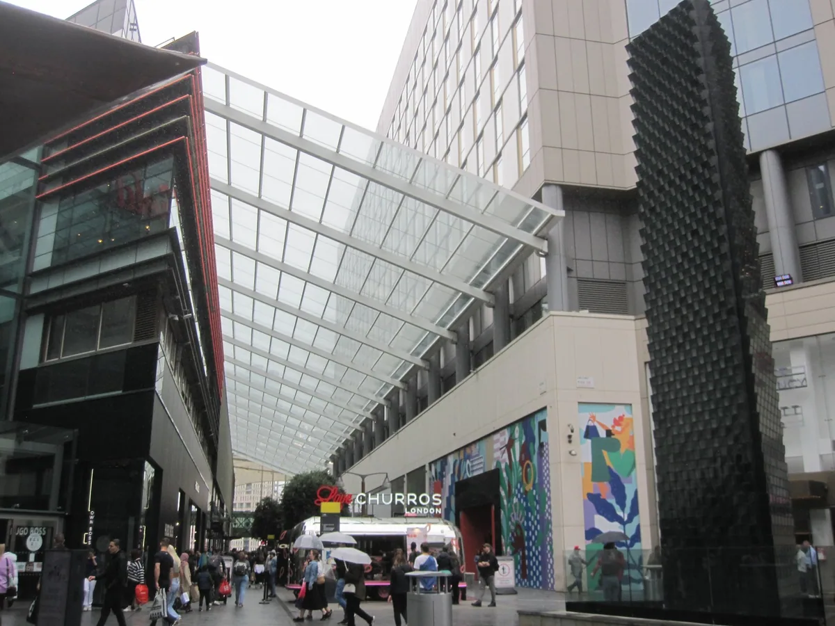 Shoppers walking along the glass-canopied open street at Westfield Stratford City