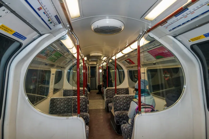Inside a 1972 stock Bakerloo line carriage, with curved white panels and red grab poles