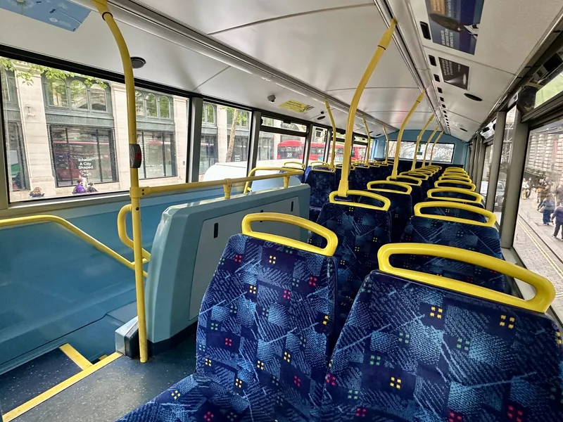 Lower deck of a London double-decker bus, with the open buggy and wheelchair bay and blue patterned seats