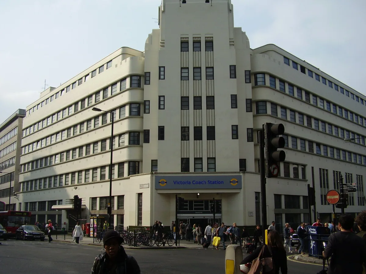The art deco frontage of Victoria Coach Station on Buckingham Palace Road, with travellers outside the entrance
