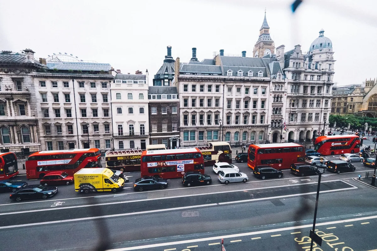 Buses, taxis and cars in heavy traffic in central London, with the tower of Big Ben above the rooftops