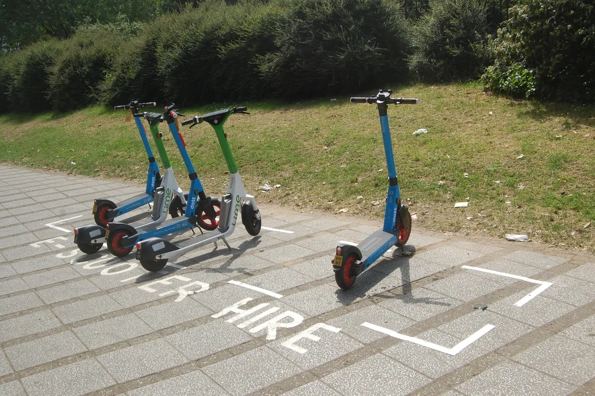 Rental electric scooters standing in a marked hire bay painted on a London pavement