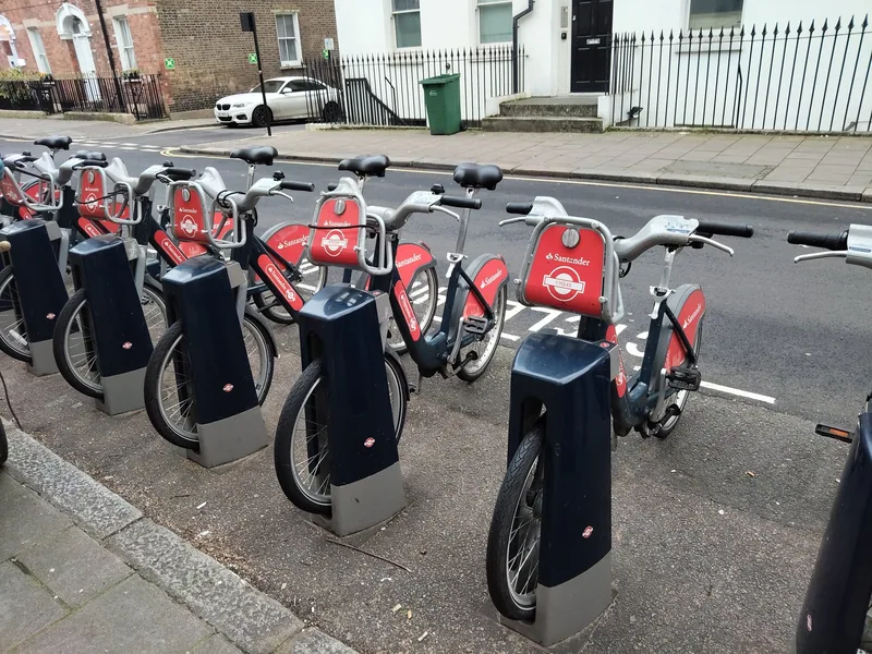 Red hire bikes lined up in a Santander Cycles docking station on a London street