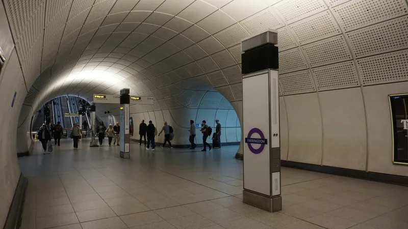 Passengers walking through a wide arched Elizabeth line station concourse with a purple roundel
