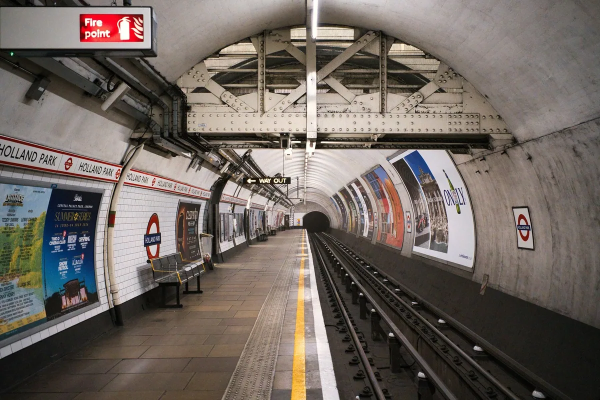 Empty deep-level Underground platform at Holland Park station with the track curving into the tunnel