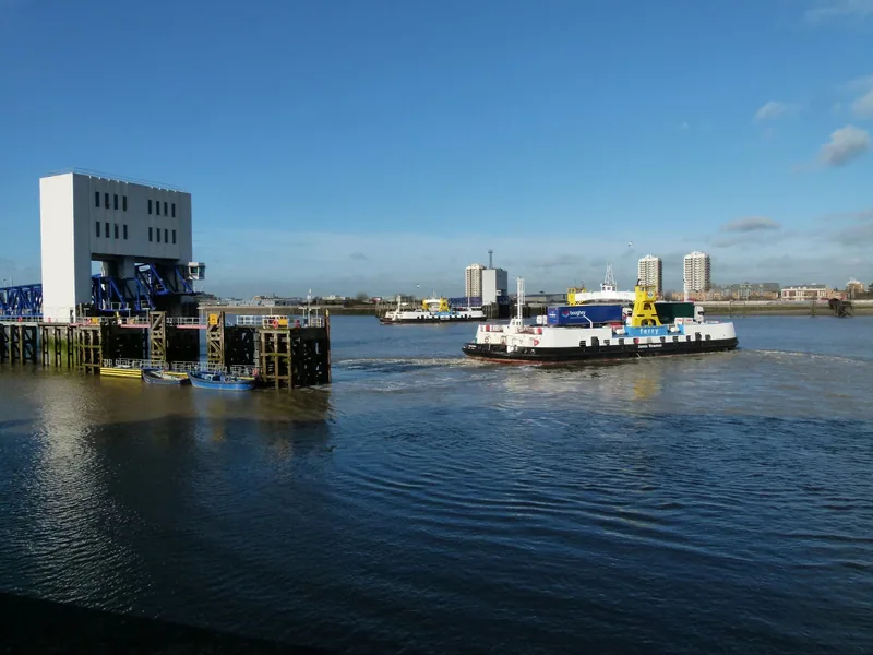 A Woolwich Ferry crossing the Thames past the terminal on a bright day