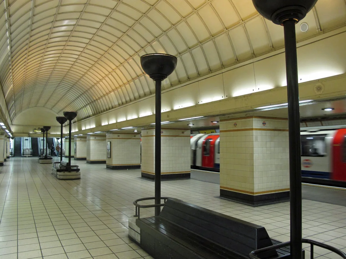 The barrel-vaulted concourse at Gants Hill station, tiled piers and uplighter columns running between the two platforms