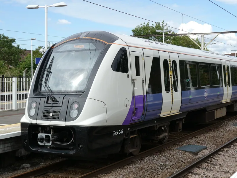 An Elizabeth line Class 345 train in its white and purple livery standing at a platform
