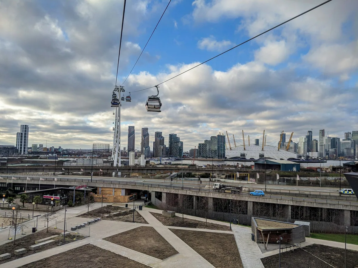 Cable car gondolas on their wires above the Royal Docks, with the O2 and Canary Wharf on the skyline