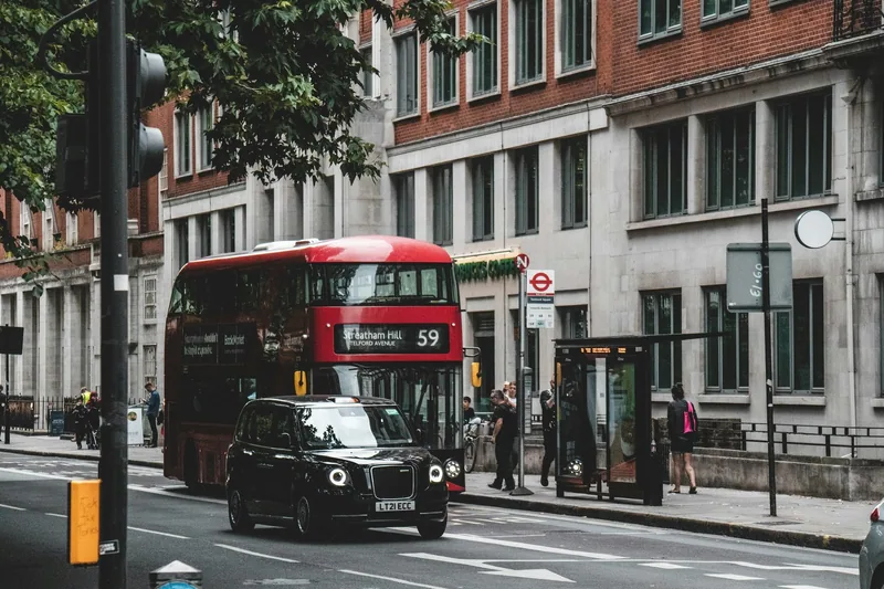 Red route 59 double-decker bus and a black cab on a London street beside a bus shelter