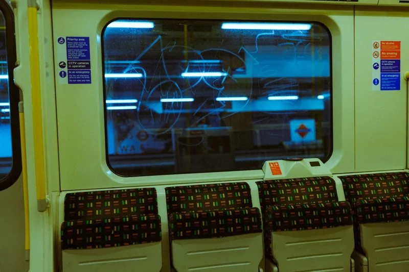 Empty late-night Tube carriage with patterned moquette seats and a dark window