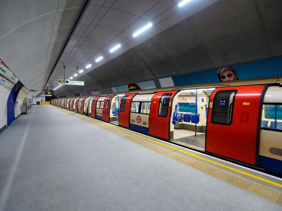 A red and cream Northern line tube train with doors open at an empty platform at Bank