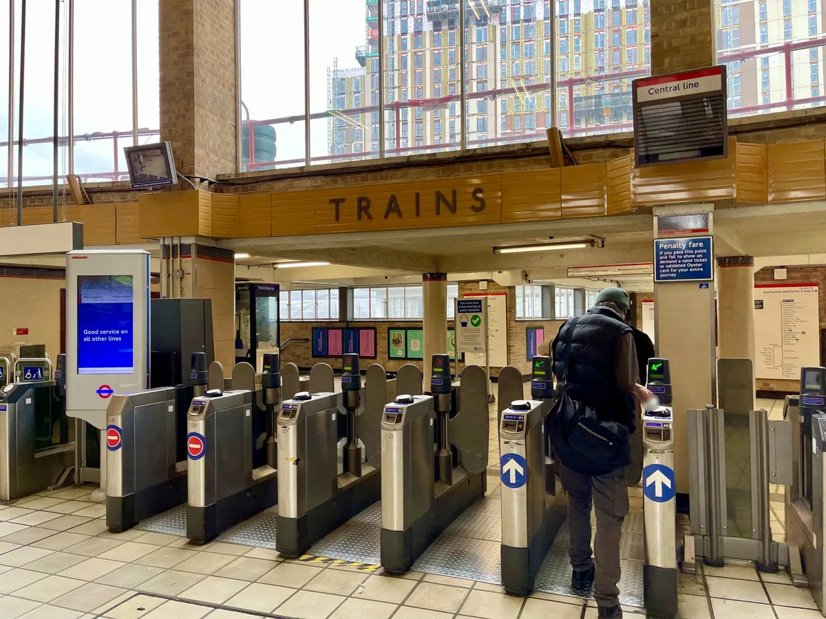 Passenger touching in at the ticket barriers in the ticket hall of White City tube station