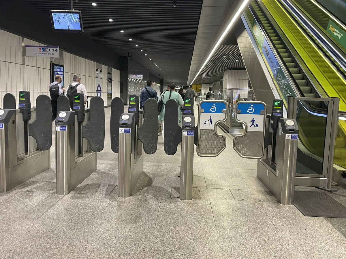 A row of ticket barriers with card readers at the Canary Wharf Elizabeth line station